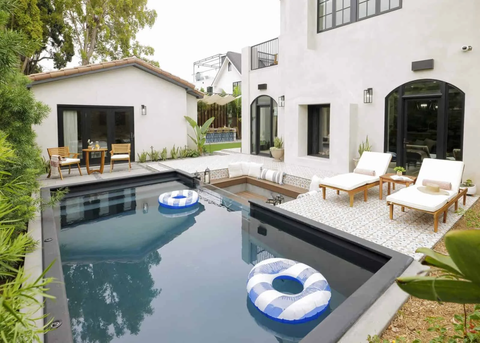 Modern backyard with a pool, lounge chairs, a sunken seating area, and a dining space