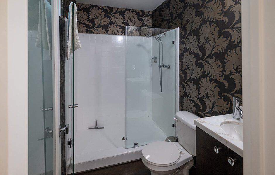 A small, modern bathroom with a white tiled shower stall and a glass door