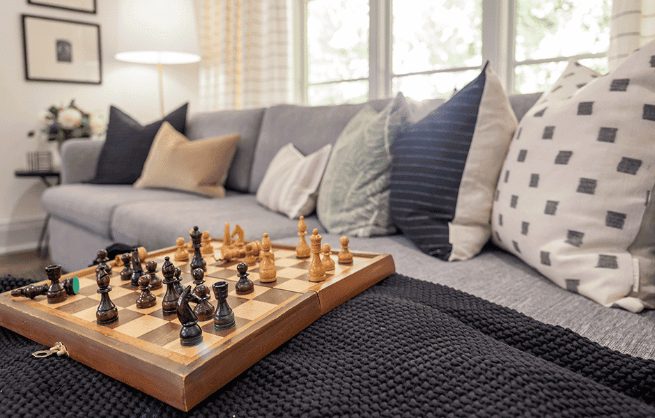 Inviting seating area featuring a gray sectional sofa, a knit blanket, and a chessboard