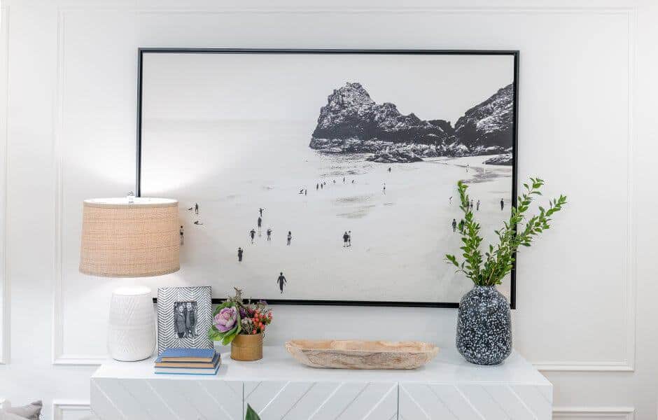 Stylish console table with a black-and-white coastal artwork, a table lamp, books, and decorative vases