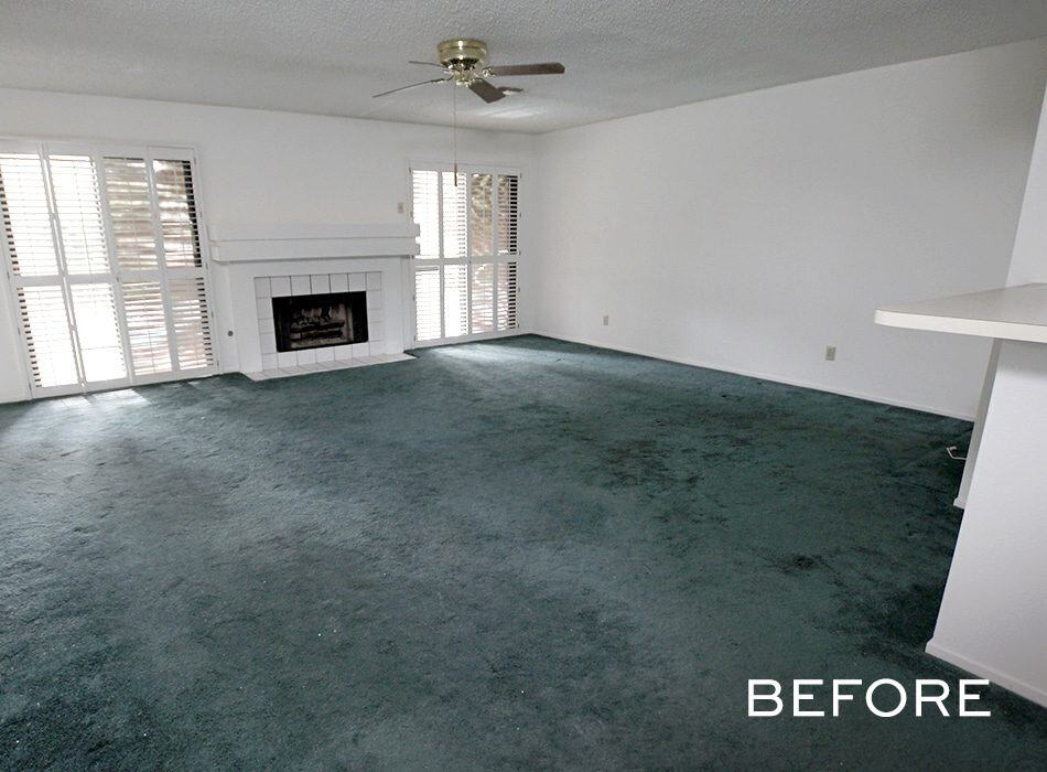 Living room with green carpet, fireplace, and ceiling fan before renovation