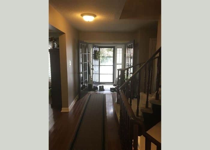 Hallway with wooden floors, staircase, and glass door framed by French doors