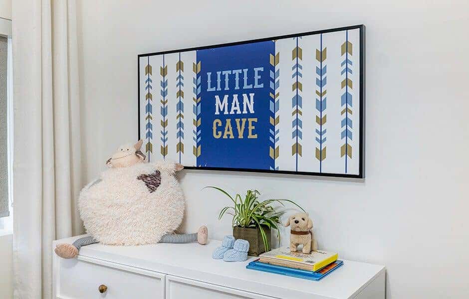 Nursery decor with "Little Man Cave" sign, stuffed toys, and a white dresser