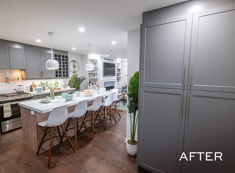 Kitchen with gray cabinets, a white countertop, and a kitchen island with bar stools (after renovation)