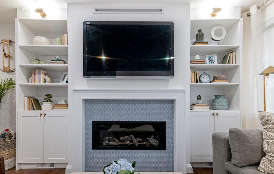 A modern living room with a TV above a white fireplace, flanked by styled built-in shelves