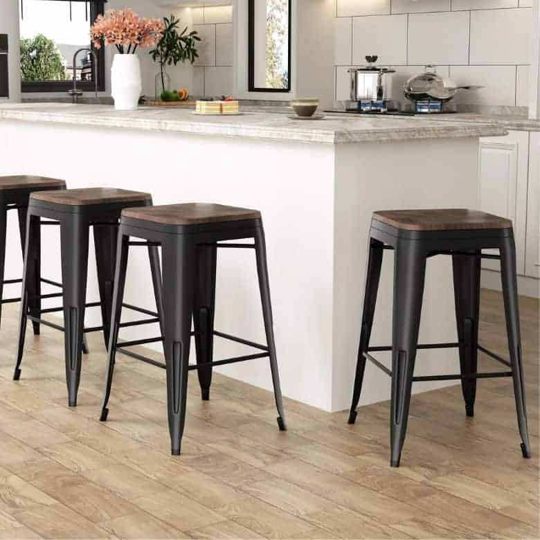 Four black metal counter stools with wooden seats, arranged around a kitchen island