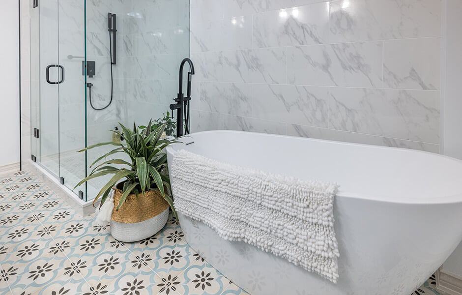 Luxurious bathroom featuring a freestanding tub, a glass-enclosed shower, and patterned floor tiles