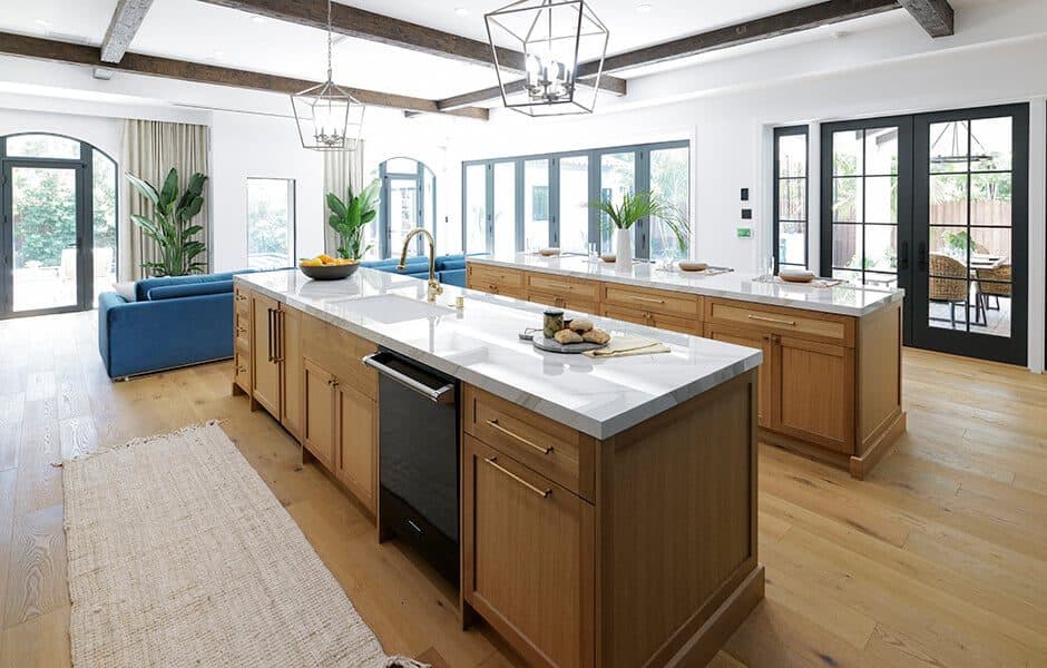 Spacious kitchen with wooden islands, white countertops, and black-framed doors