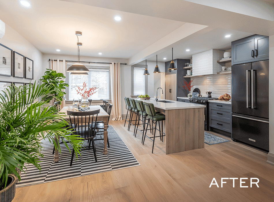 Modern dining and kitchen area with a wooden table, striped rug, green stools, and black cabinetry