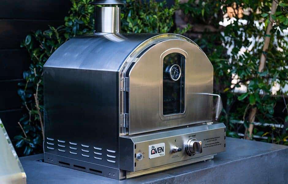 Stainless steel outdoor pizza oven with a temperature gauge and modern design