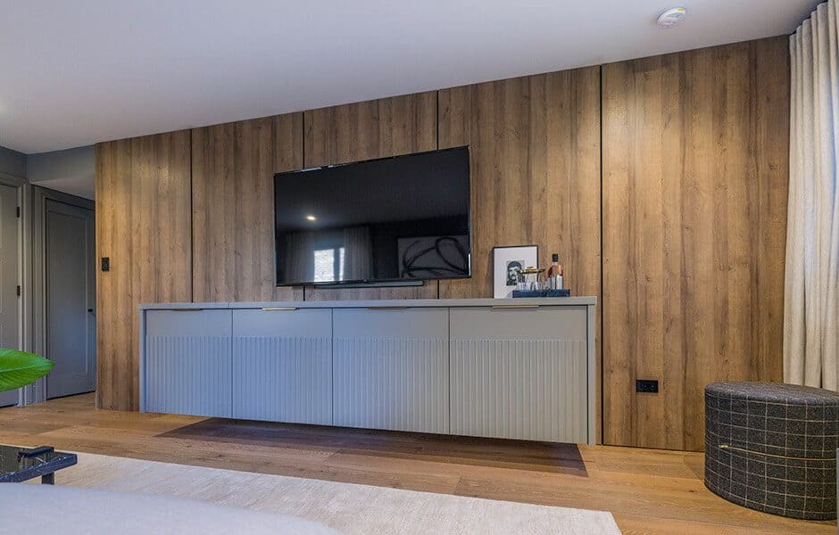 Living room with a wood-paneled wall, a mounted television, and a gray floating console table