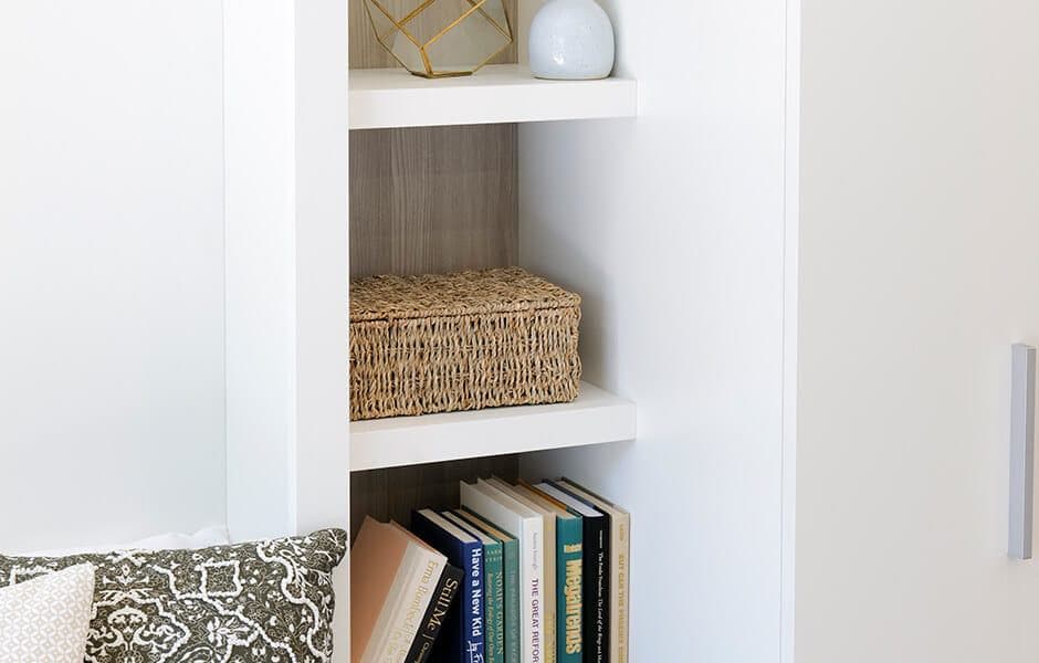 White shelving with books, a woven basket, and decorative items