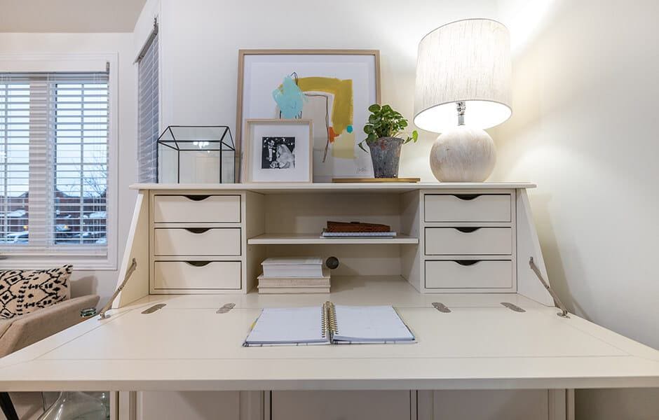 Compact white desk with drawers, lamp, and decorative accents