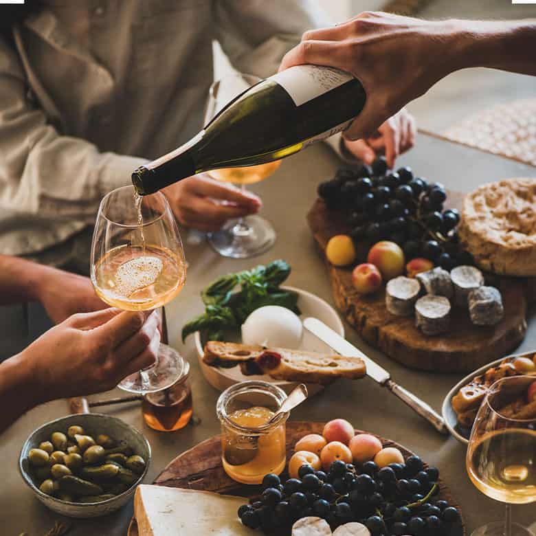 pouring wine for friends around a snack board