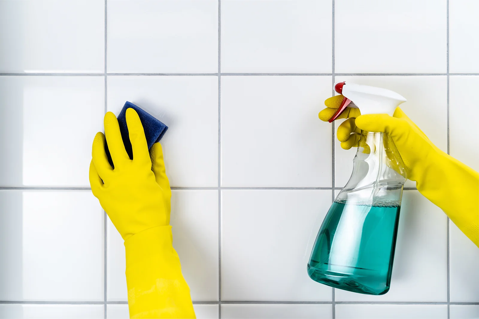 cleaning grout with gloves and a spray bottle